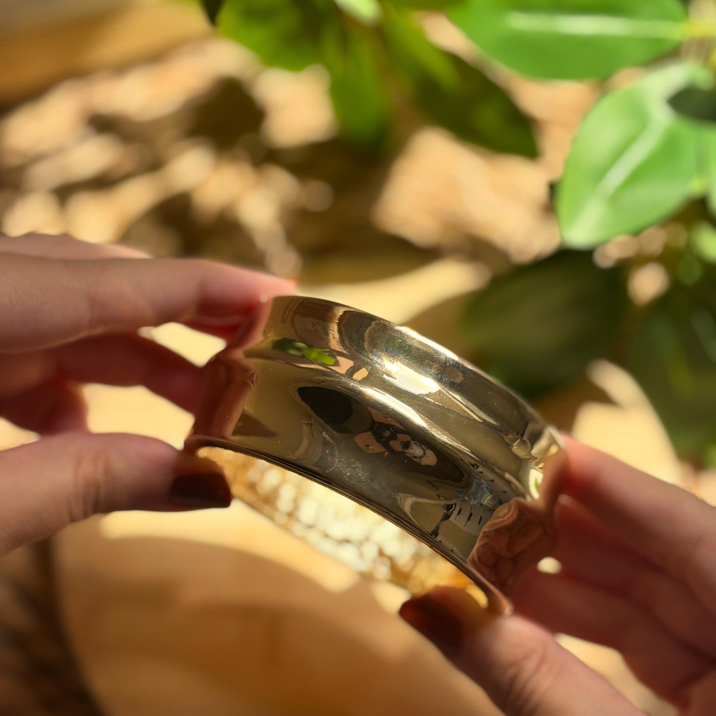 Silver bracelet held by a person with a natural background