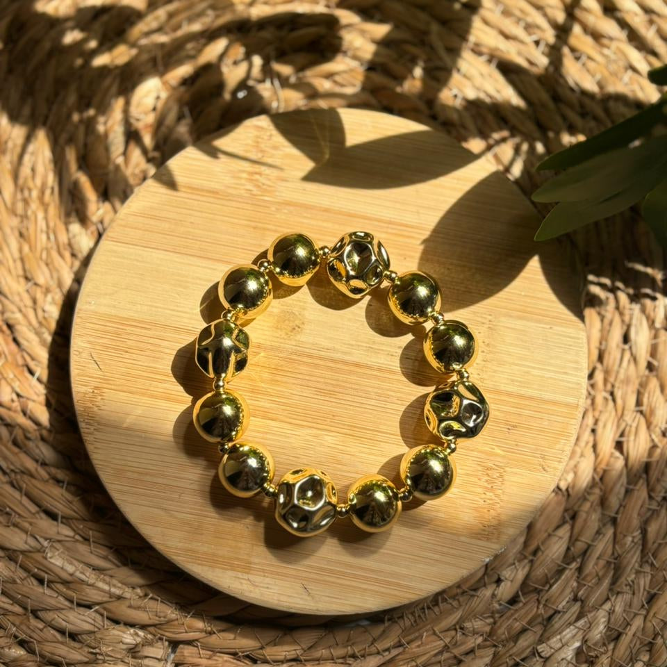 Gold beaded bracelet on a wooden surface with natural light