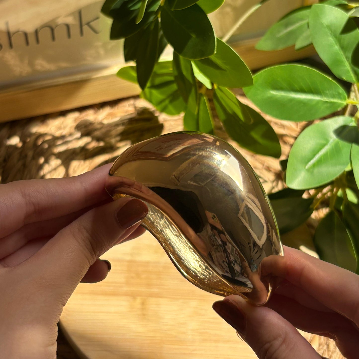 Gold heart-shaped object held by hands with a blurred background